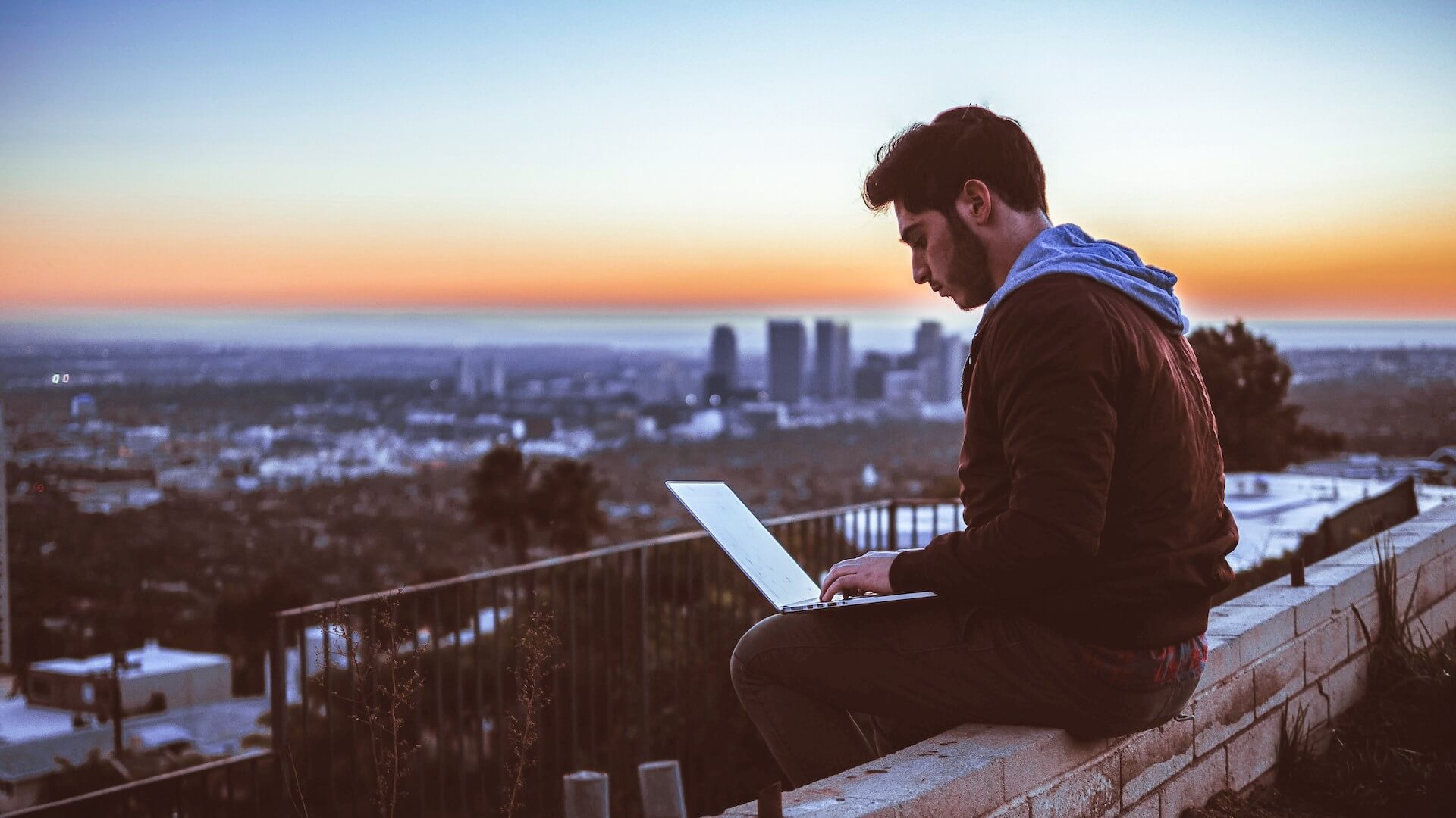 Man on a roof on laptop doing virtual sales